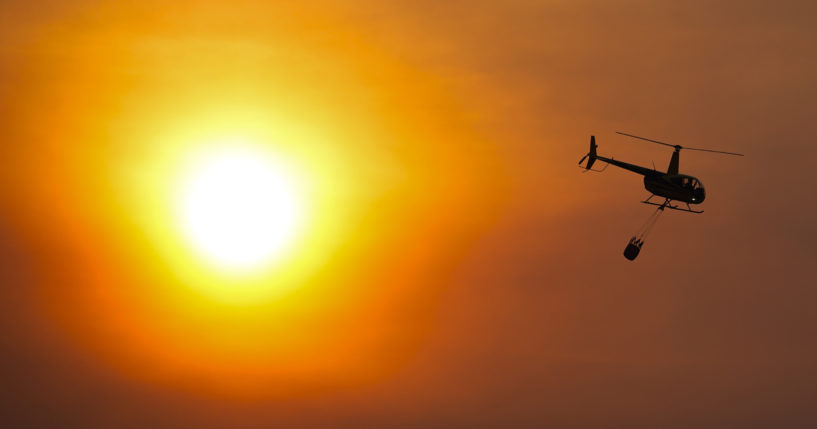 A helicopter carries a water bucket as it flies over homes burned by the Smokehouse Creek Fire Feb. 28 in Canadian, Texas.