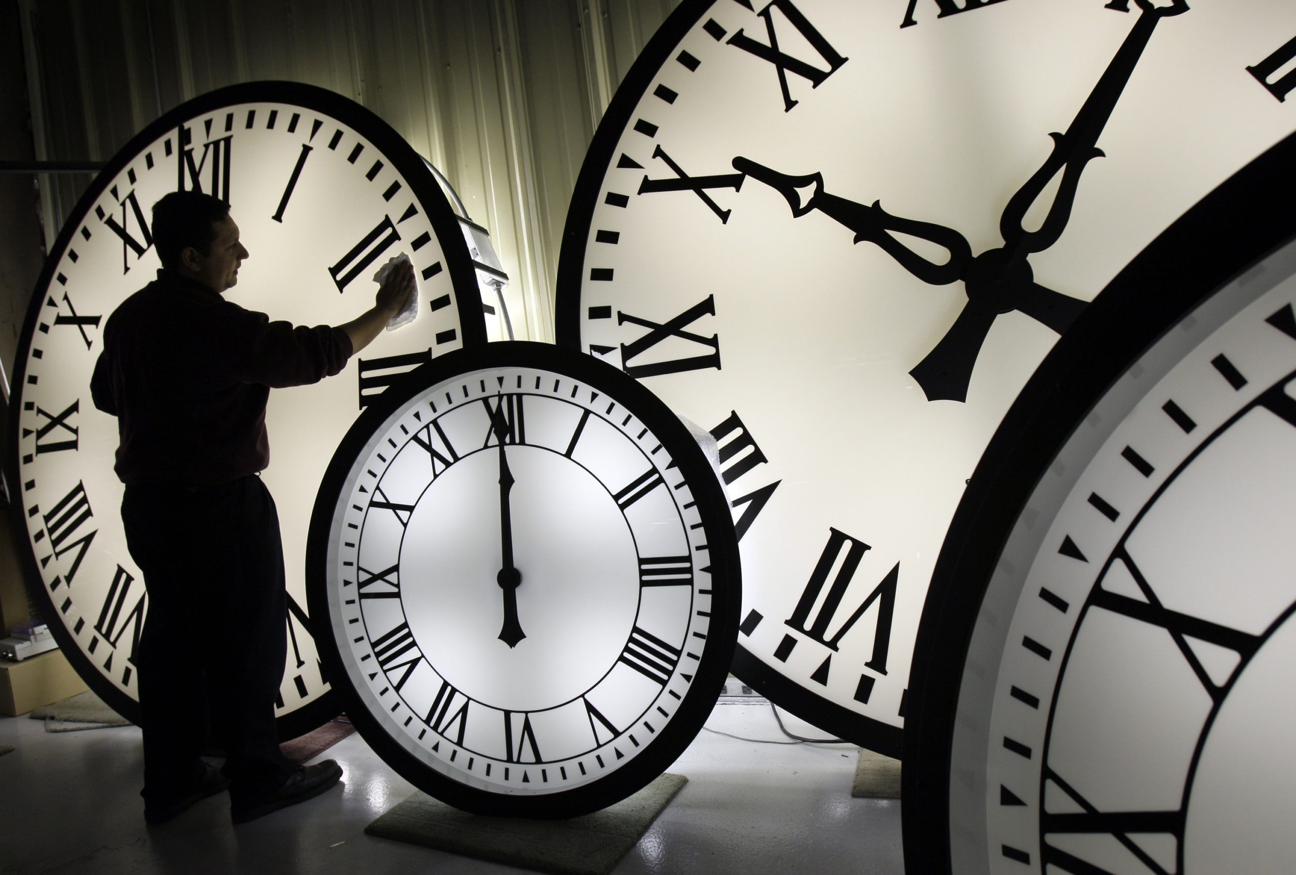 An Electric Time Co. employee cleans the face of an 84-inch Wegman clock at the plant in Medfield, Massachusetts, in 2008. Most Americans will set their clocks forward by one hour this weekend, to daylight saving time.