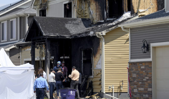 Investigators stand outside a house where five members of a Senegalese family were found dead after a fire in Denver on Aug. 5, 2020.