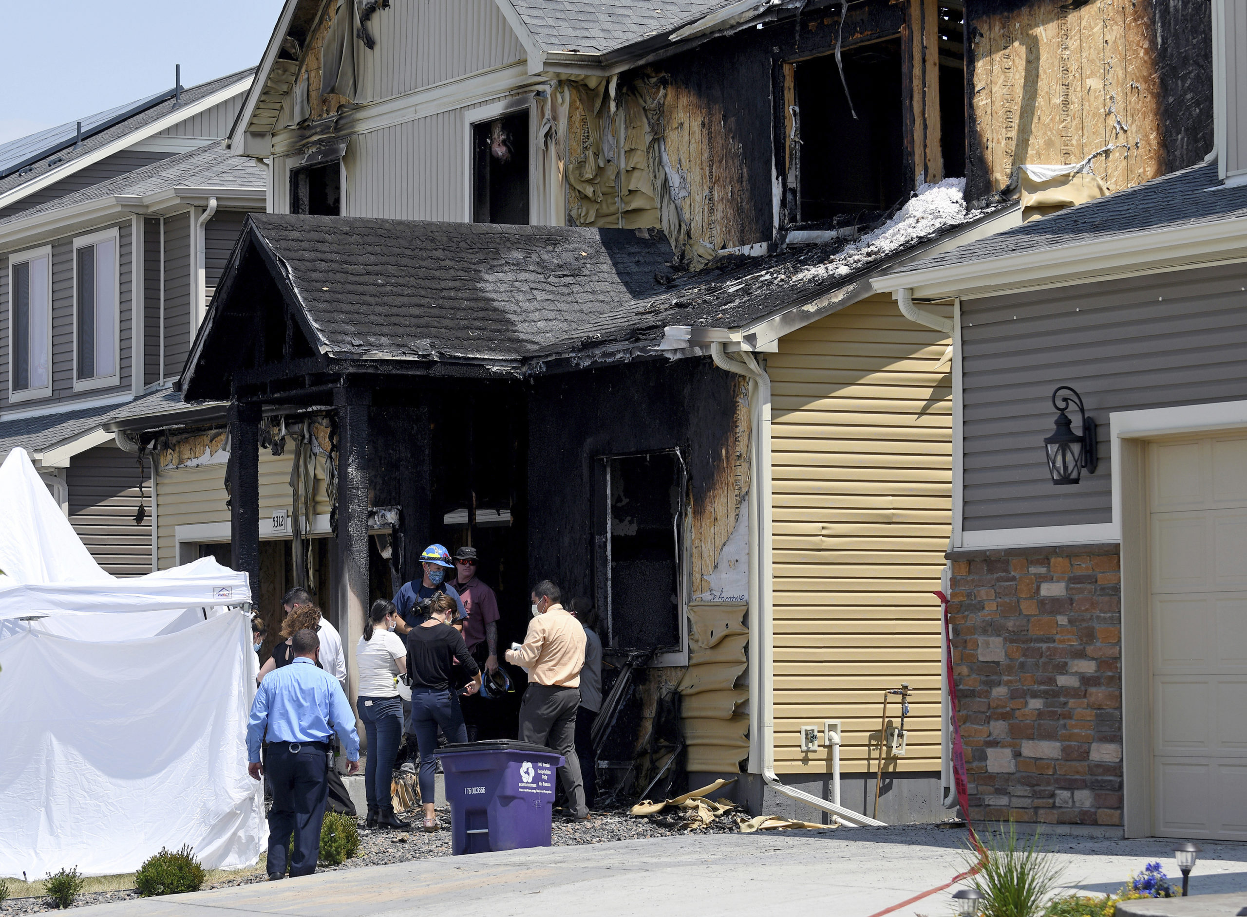 Investigators stand outside a house where five members of a Senegalese family were found dead after a fire in Denver on Aug. 5, 2020.