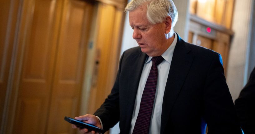 Sen. Lindsey Graham looks at his phone as he walks toward the Senate Chamber on Capitol Hill in Washington on April 23.