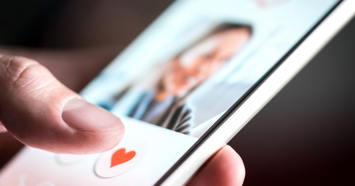 This image shows a young man's hand as he is swiping and liking profiles on a relationship site.