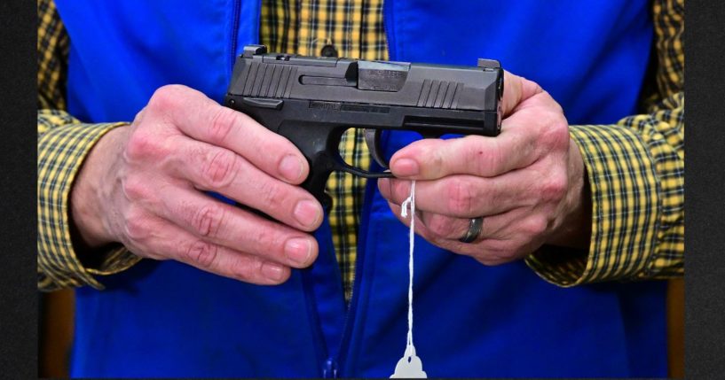 A gun shop owner displays a Sig Sauer pistol in a file photo from Feb. 24.