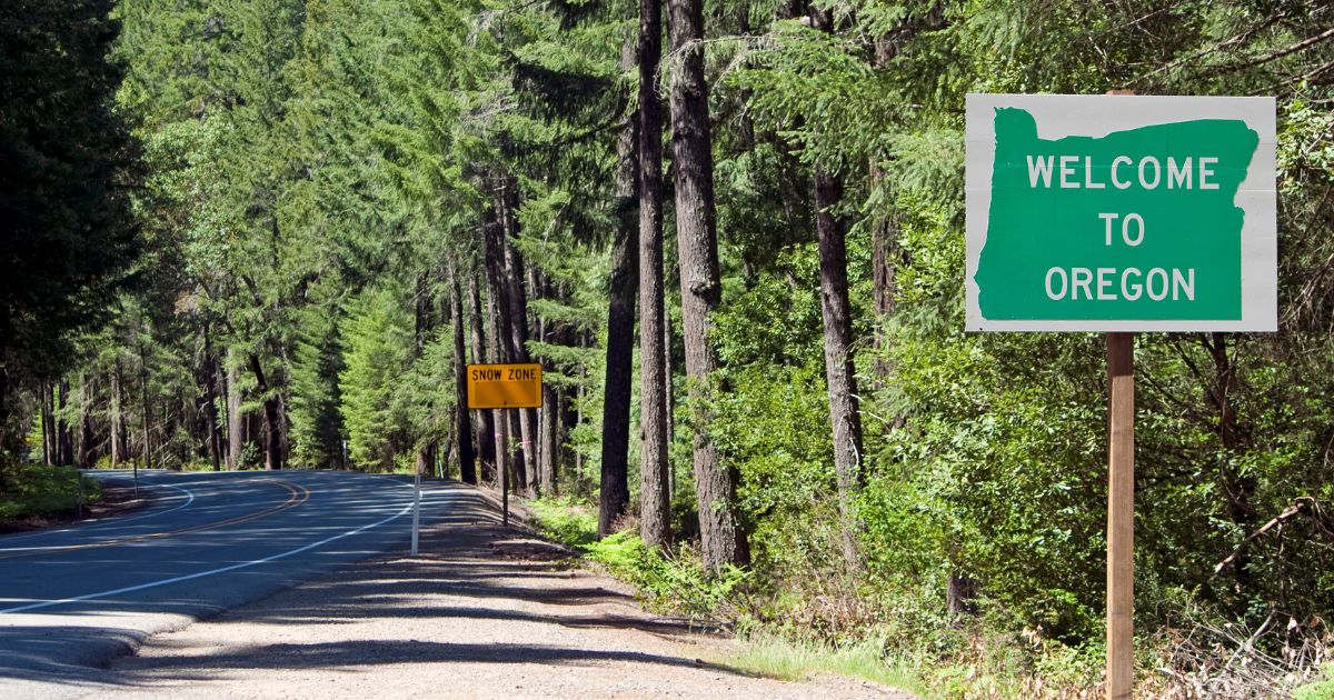 a roadside sign in the forest that says "welcome to Oregon"