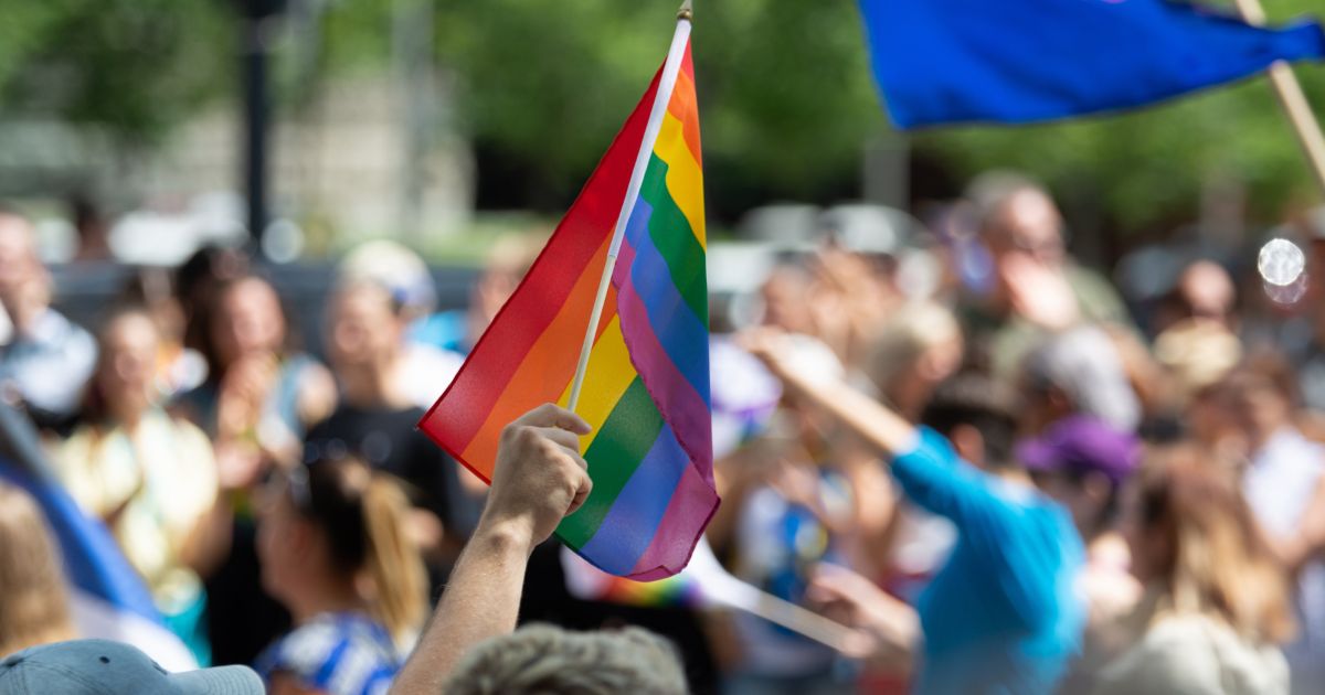 This image shows a group of people that are a part of a "Pride" parade in Montreal, Canada. One person is waving a rainbow flag.