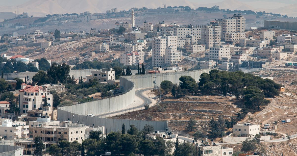 This image shows an overview into the West Bank and a view of the wall separating East Jerusalem as viewed from the Mount of Olives.