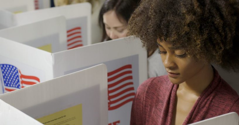 Two young women cast their vote at a polling station.