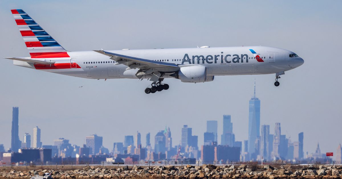 A Boeing 777 passengers aircraft of American Airlines arrives from Milan at JFK International Airport in New York as the Manhattan skyline looms in the background on February 7, 2024.