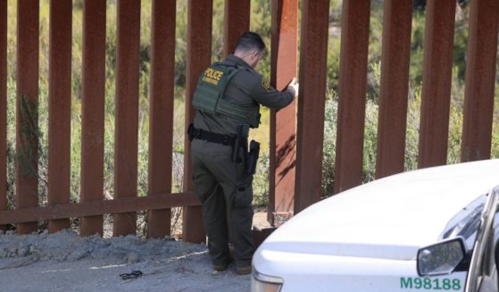 A US Border agent examines a vandalized section of the US-Mexico border fence near Campo, California, on April 4, 2024.