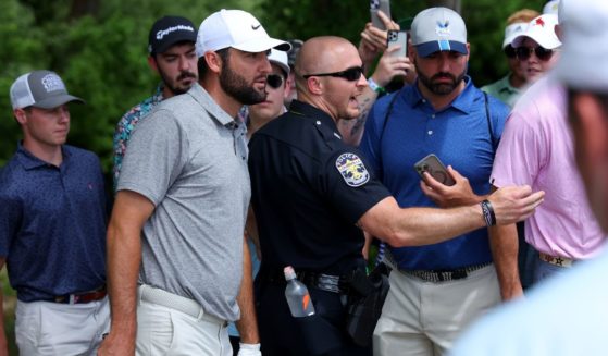 Spectators and a security guard look on as Scottie Scheffler prepares to take a drop on the fourth hole during the third round of the 2024 PGA Championship at Valhalla Golf Club on Saturday in Louisville, Kentucky.