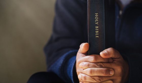 This photo shows hands holding tightly to the Holy Bible.