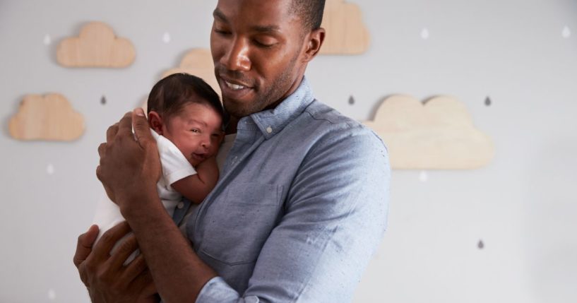 This image shows a father holding his newborn son in the nursery.