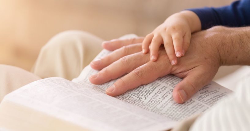 A man reads to a young child from the Bible.