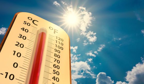 This stock image shows a thermometer with extreme summer temperatures under a bright sun.
