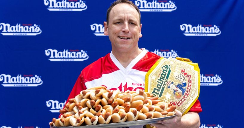 Competitive eater Joey Chestnut poses for photos with 76 hot dogs at a weigh-in before the Nathan's Famous July Fourth hot dog eating contest in New York on July 1, 2022.