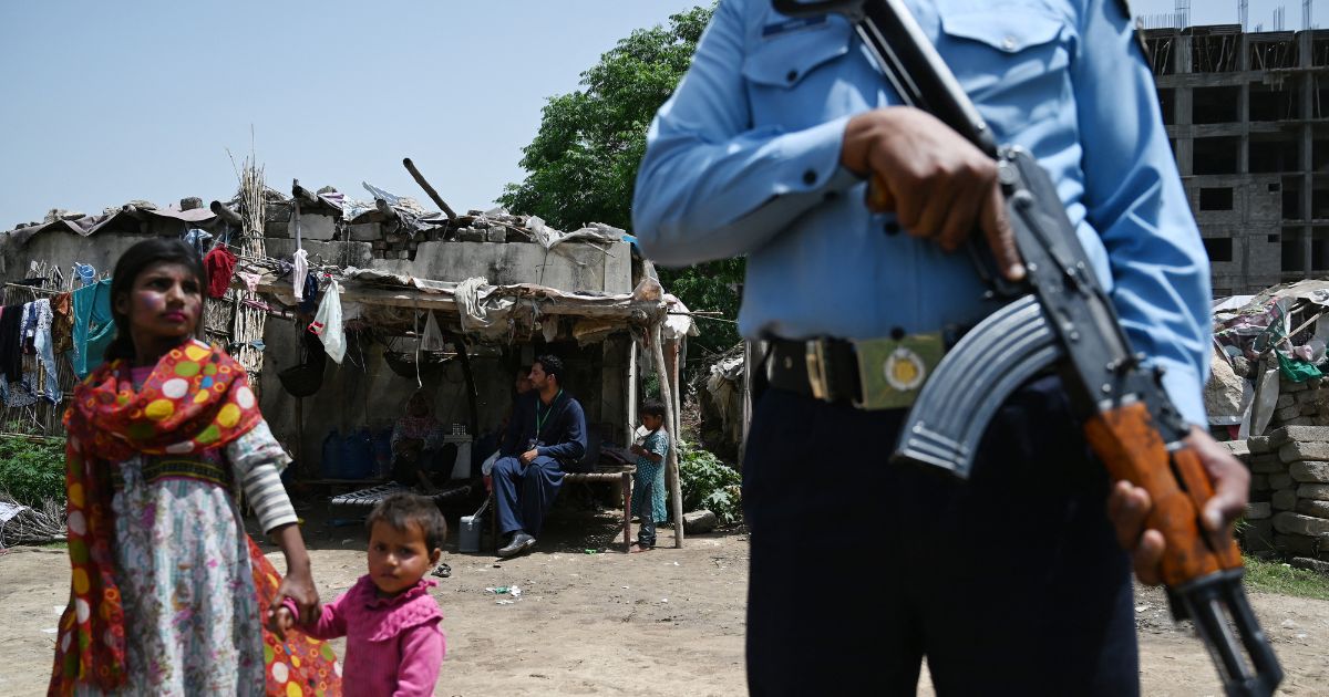A Pakistani police officer stands guard as health workers engage in a door-to-door polio immunization campaign on the outskirts of Islamabad on April 26, 2019.