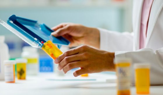 This stock image shows a close-up of a pharmacist filling a prescription.