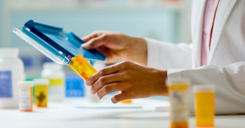 This stock image shows a close-up of a pharmacist filling a prescription.