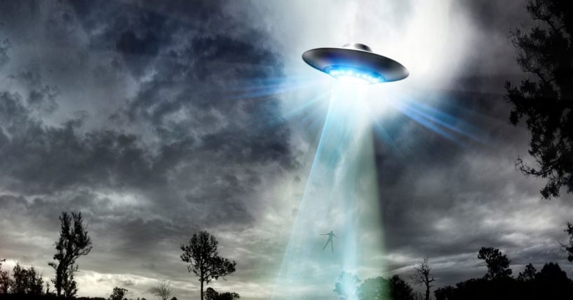 This stock illustration depicts a UFO beaming up a human.