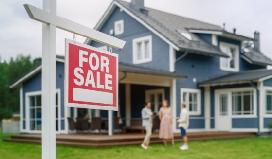 a young couple talking with a real estate agent outside a home for sale