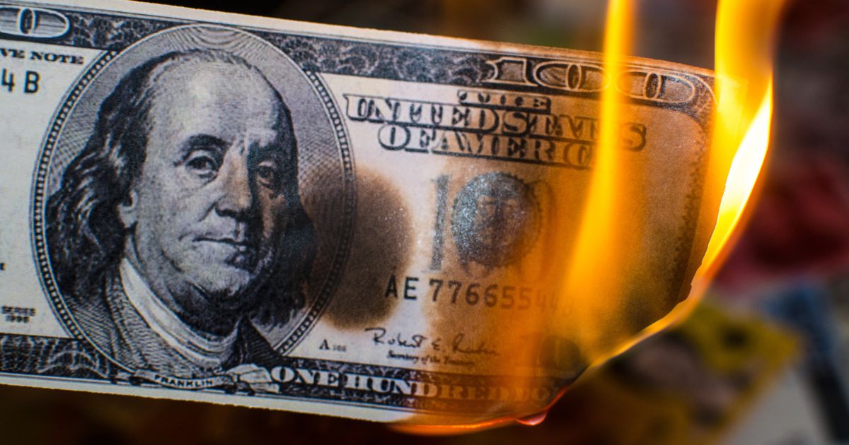 A stock photo shows a U.S. hundred-dollar bill on fire.